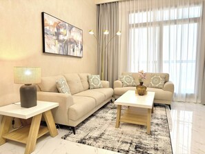 Ein modernes Wohnzimmer mit einem beigen Sofa, einem Couchtisch, einer Lampe und einem Bild an der Wand.