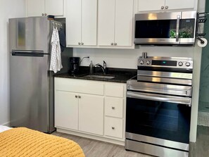 Una cocina moderna con electrodomésticos de acero inoxidable, incluyendo un refrigerador, microondas y horno.