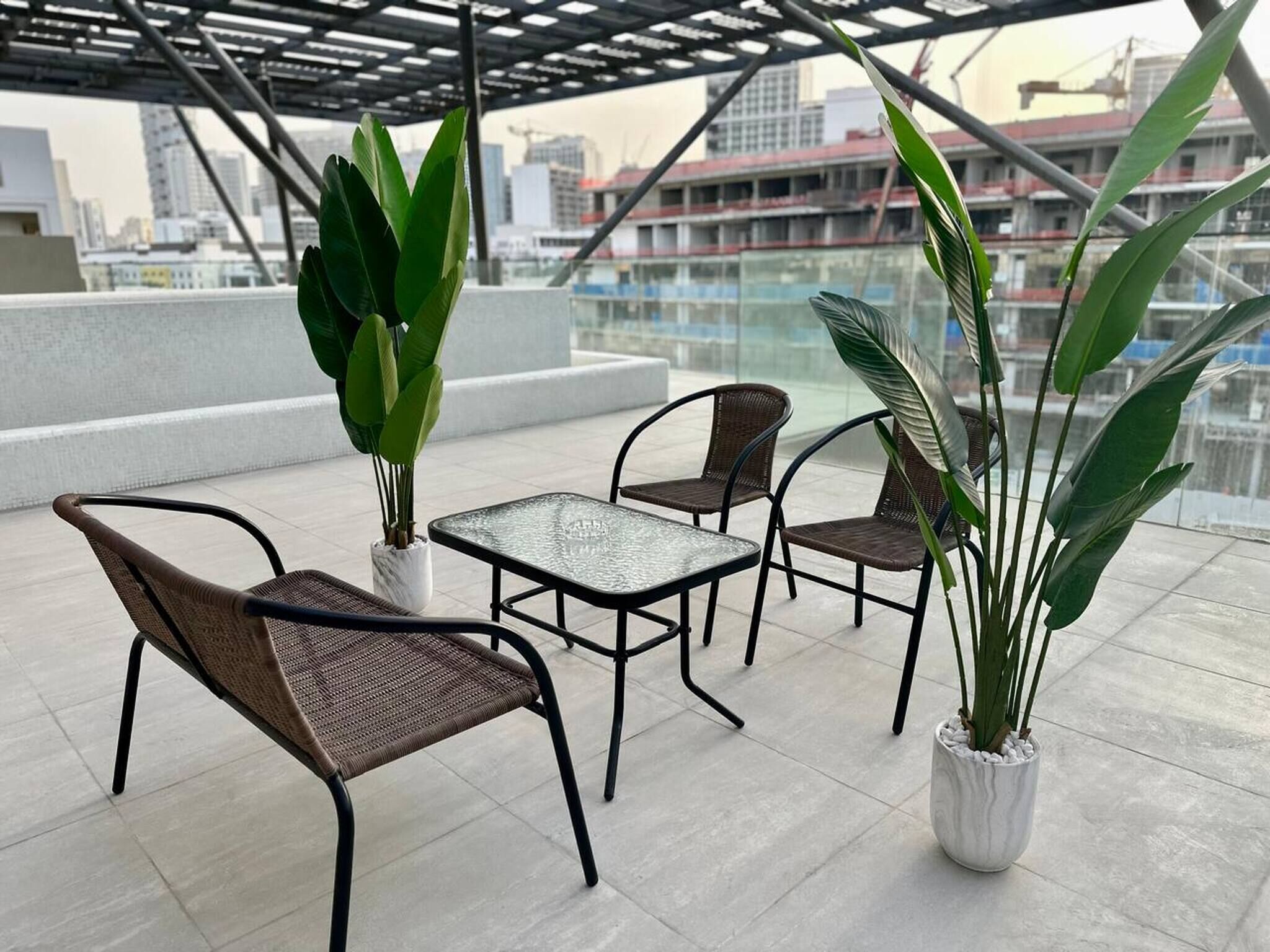 A rooftop terrace with outdoor furniture and potted plants.