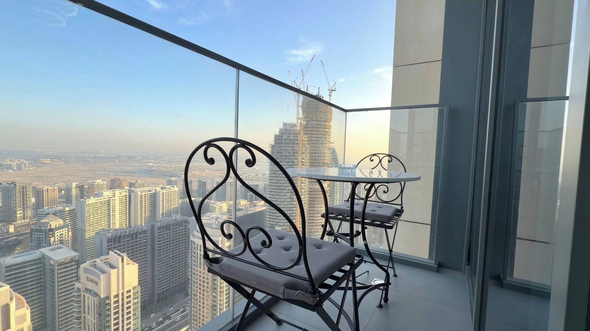 A balcony with a table and chairs, offering a city view.