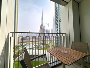 A balcony with a view of a cityscape including a tall skyscraper, a pool, and surrounding buildings. - Burj Khalifa View Opposite to Dubai Mall Luxury 2B (Dubai)