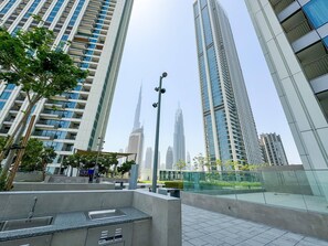 A modern urban setting with high-rise buildings, a clear sky, and a public space with seating and greenery. - Burj Khalifa View Opposite to Dubai Mall Luxury 2B (Dubai)