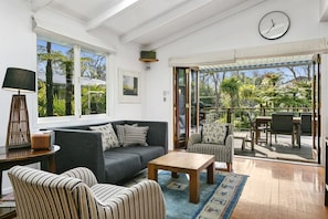 A modern living room with a sofa, armchairs, a coffee table, and a dining area with chairs and a table. - Stunning Four Bedroom home near the lake (Taupō)