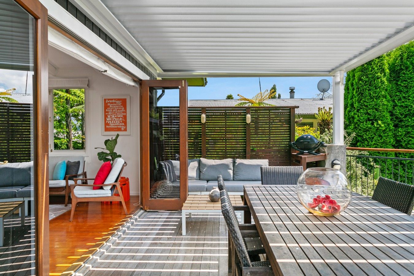 A covered outdoor patio with a wooden table, chairs, and a sofa.
