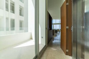 Un interior modern amb una paret de vidre, una porta de fusta i un passadís que condueix a una zona de menjador.