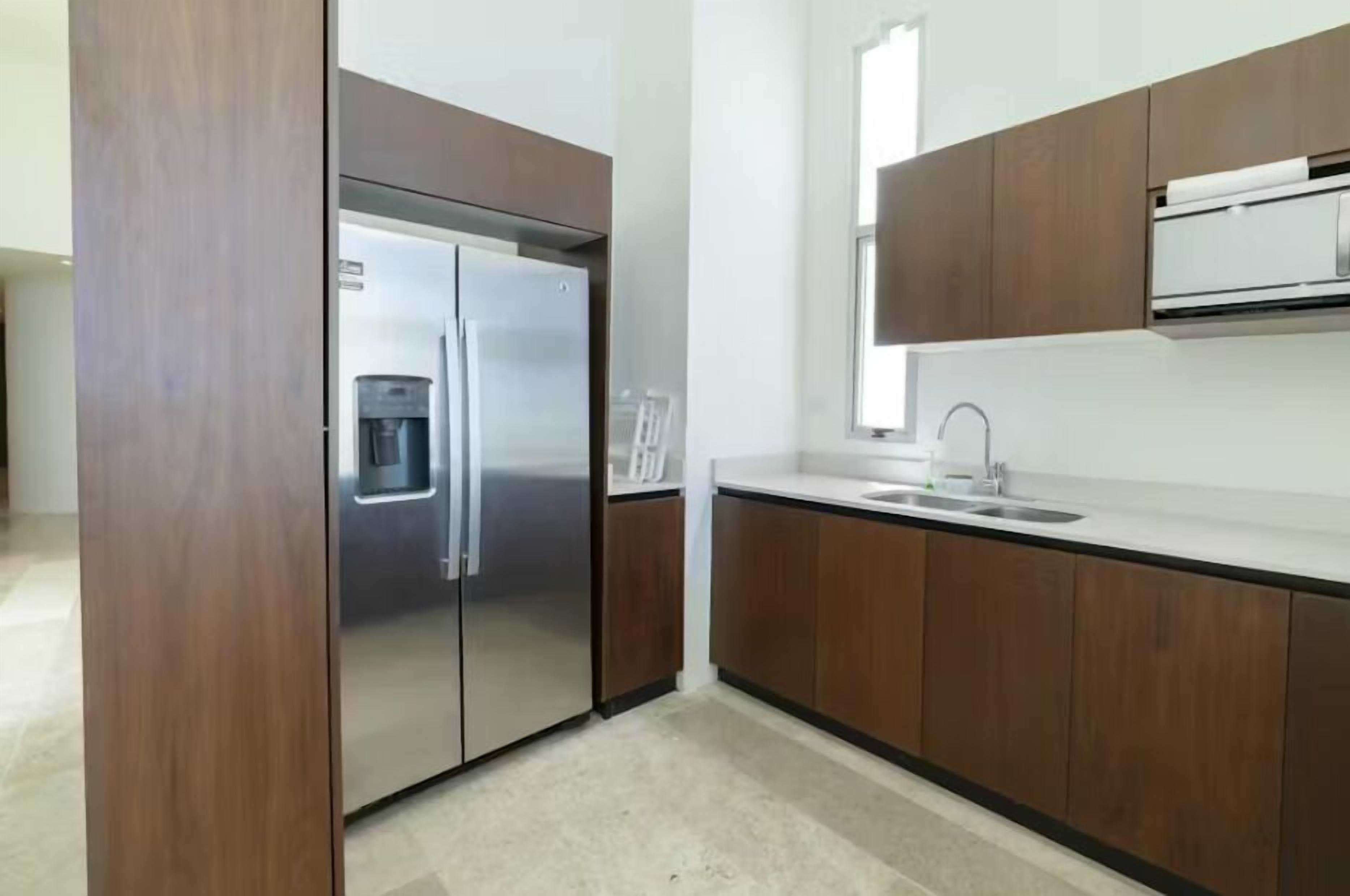 A modern kitchen with stainless steel appliances, wooden cabinets, and a white countertop.