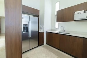 Une cuisine moderne dotée d’appareils électroménagers en acier inoxydable, de meubles en bois et d’un plan de travail blanc.