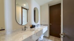 A bathroom with two sinks, a large mirror, and a door.