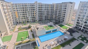 Ein Hochhaus mit Wohnetagen, mehreren Balkonen, einem Dachpool und einem begrünten Innenhof.