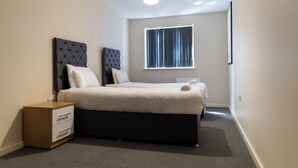 Quarto com cama, mesas de cabeceira, janela e luminária no teto.
