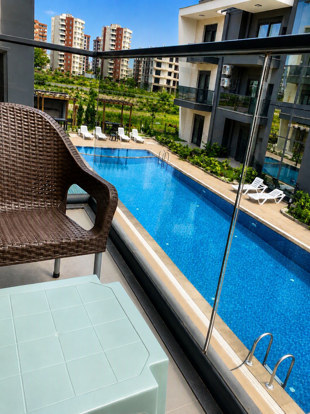 Un apartamento moderno con vista a una piscina, sillas de descanso y un balcón.