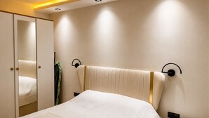 Ein Schlafzimmer mit einem Bett, einem Nachttisch, einem Spiegel und einer Wandleuchte.
