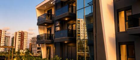 A modern building with a pool, multiple balconies, and a clear sky.