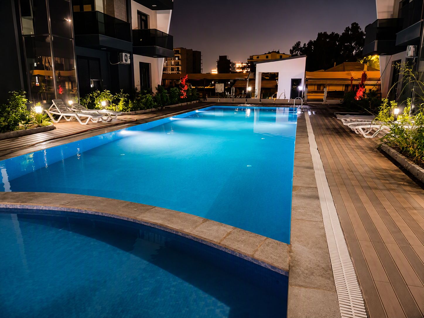A swimming pool with lounge chairs and a wooden deck.