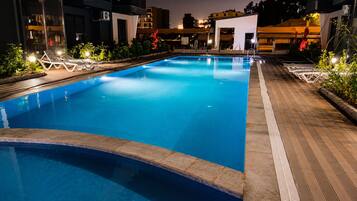 A swimming pool with lounge chairs and a wooden deck.