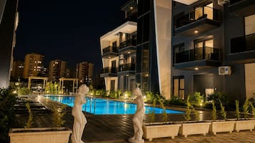 Un edificio moderno con piscina, iluminación exterior y una estatua.