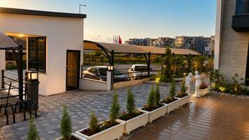 A modern outdoor patio area with a carport, potted plants, and a statue.