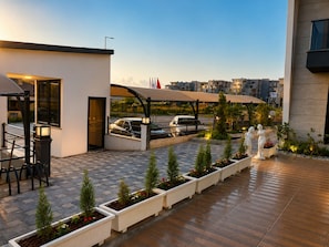 A modern outdoor patio area with a carport, potted plants, and a statue. - Armin Luxury Suite (Antalya)