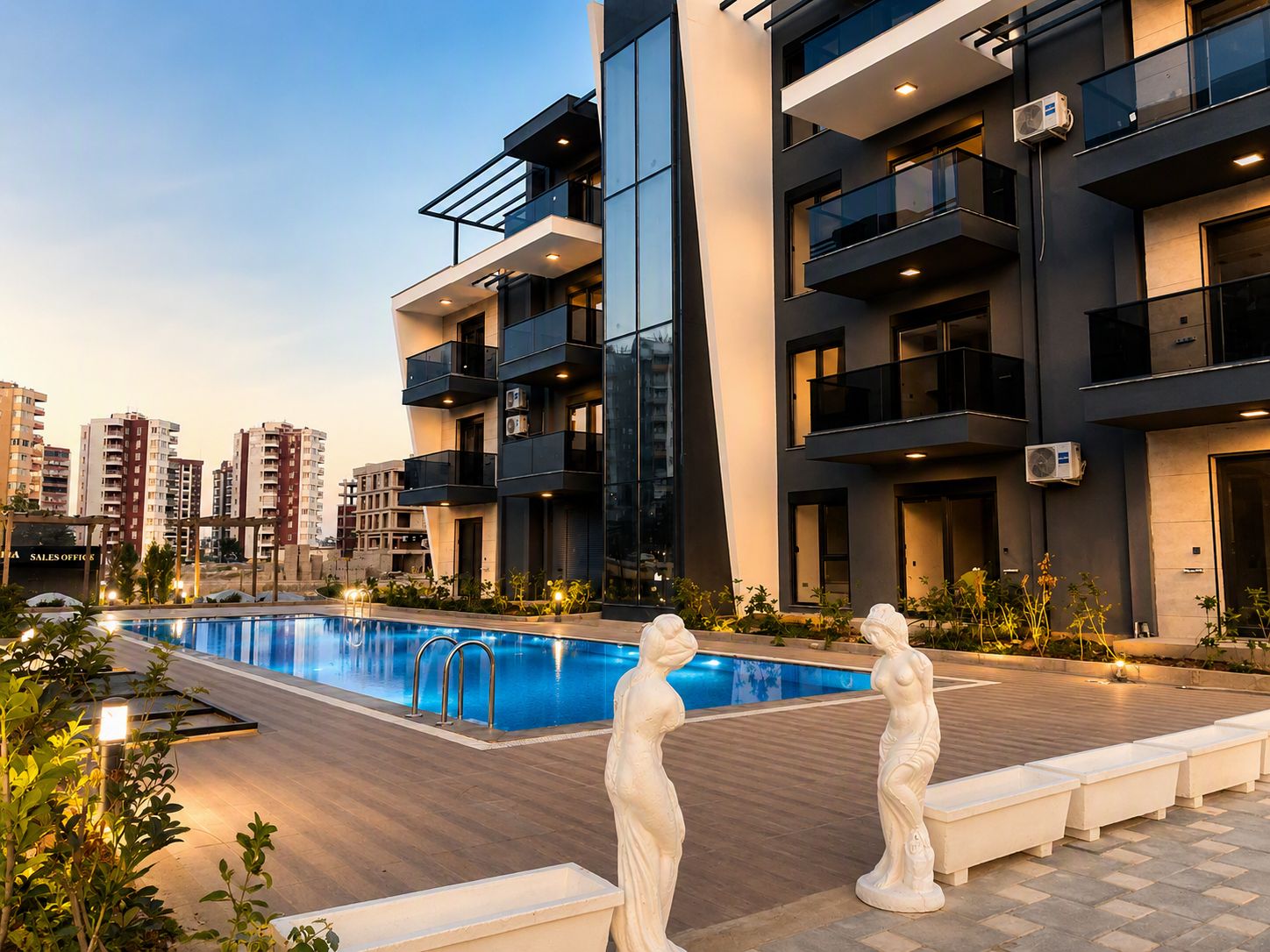 A modern apartment building with a swimming pool, outdoor lighting, and decorative statues.