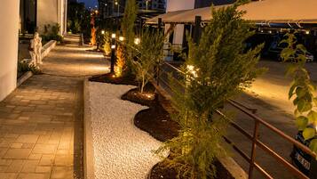 A nighttime outdoor pathway with gravel, small trees, and a statue.