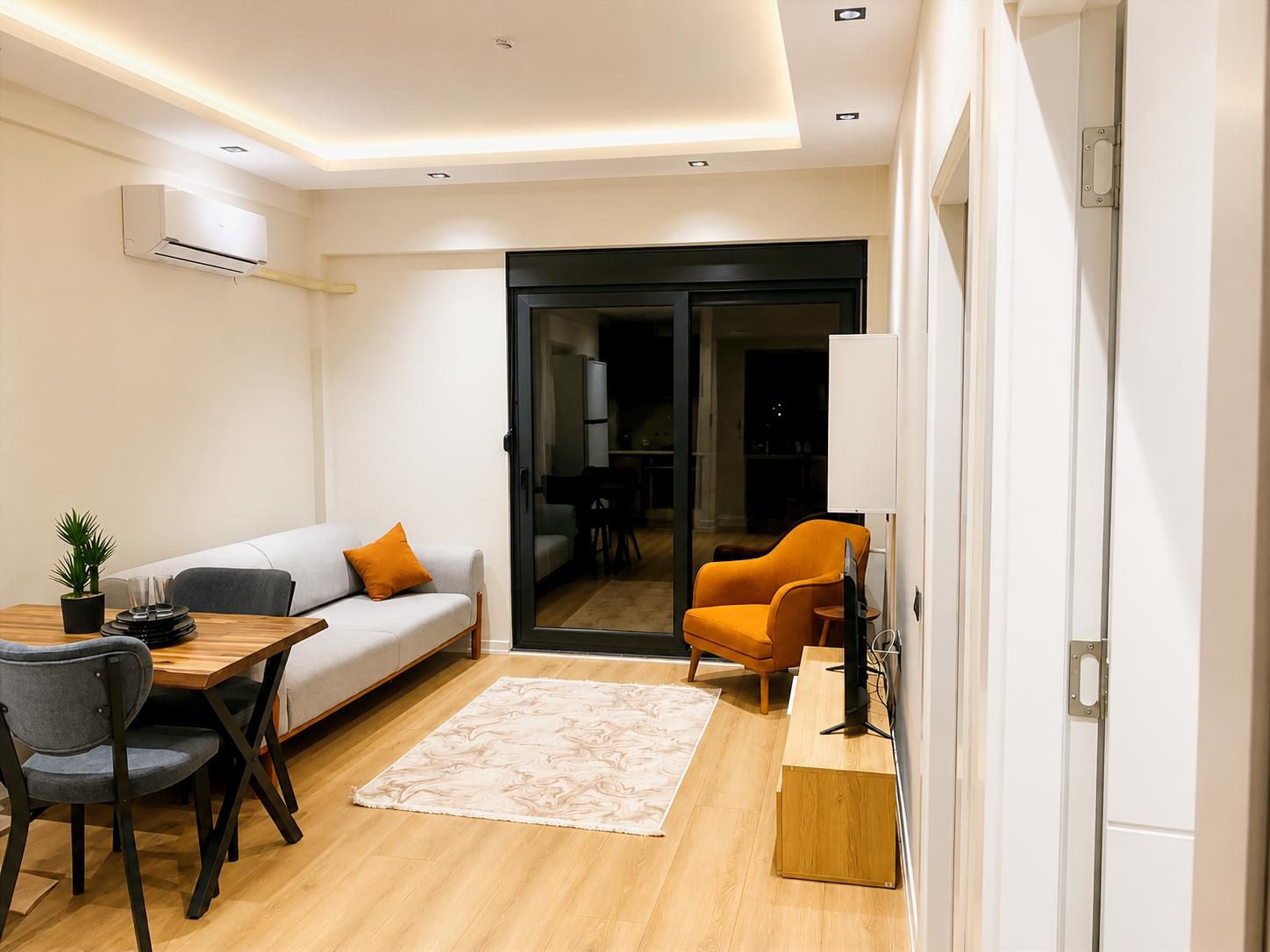 Una sala de estar moderna con un sofá, una mesa de comedor y un mueble para la televisión.