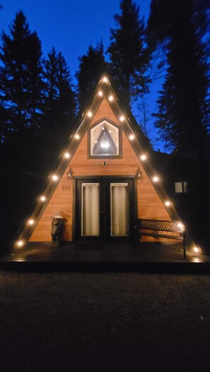 A wooden cabin with a triangular roof, a front door, and a small porch area. - A cozy A-Frame cabin for 2, just minutes from Mt. Rainier National Park (Ashford)