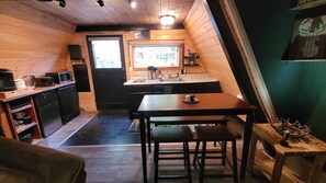 A compact kitchen with a dining area, wooden walls, and a window. - A cozy A-Frame cabin for 2, just minutes from Mt. Rainier National Park (Ashford)