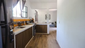 Een moderne keuken met houten kastjes, een ingebouwde oven en een aanrecht met een koffieapparaat.