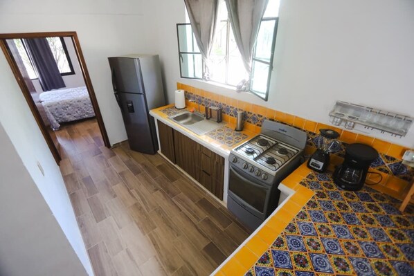 A compact kitchen with a refrigerator, stove, and coffee maker.