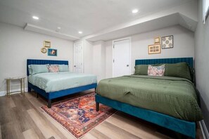 Ein Schlafzimmer mit zwei Betten, einem gemusterten Teppich und einer weißen Tür.