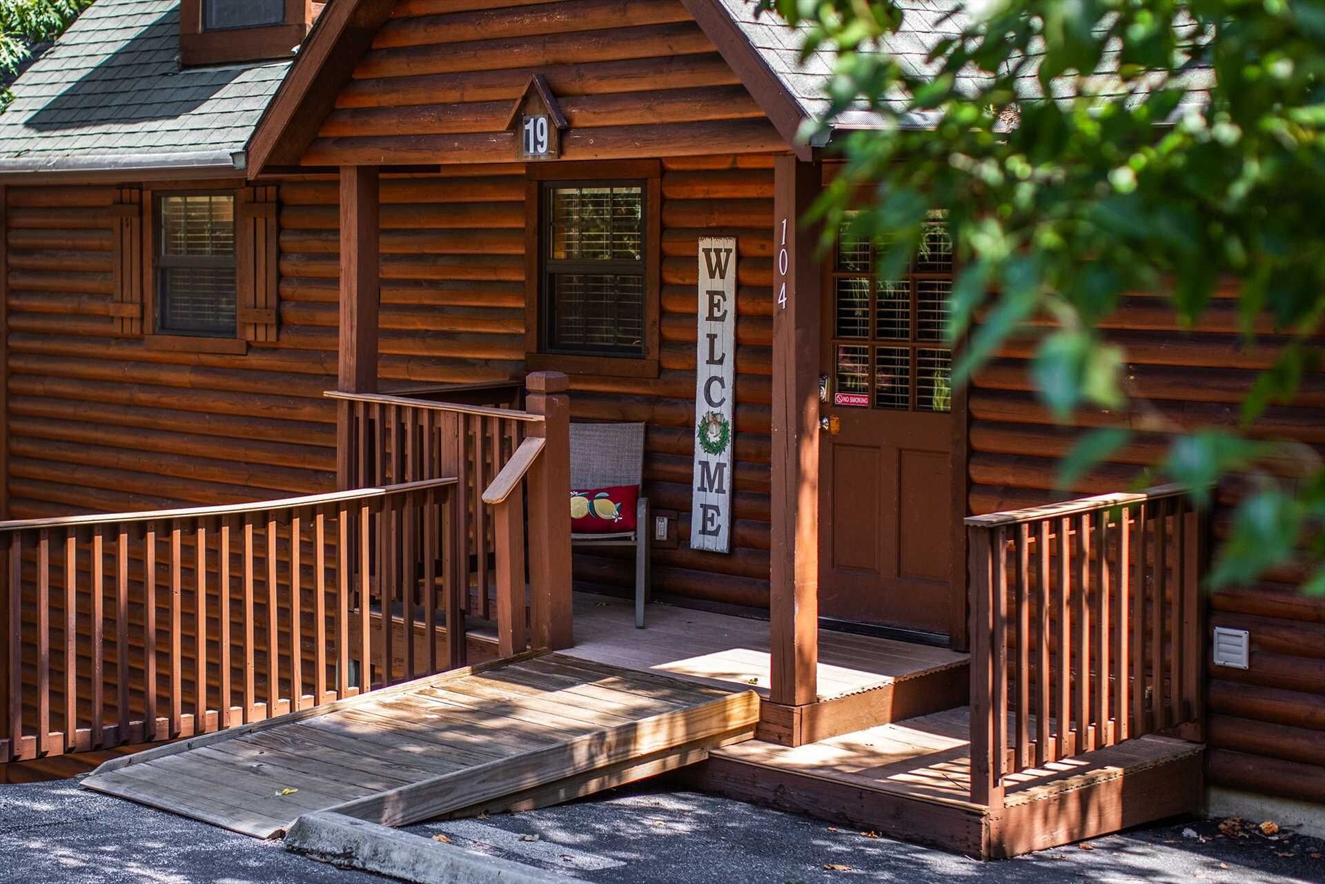 Une cabane en bois avec une pancarte « BIENVENUE », une véranda dotée d’une rampe d’accès et une pancarte « DÉFENSE DE FUMER ».