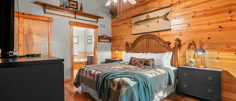 A wooden-paneled bedroom with a bed, nightstands, a ceiling fan, and a fish mural.