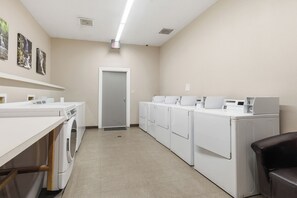 A laundry facility with multiple washing machines and dryers, a wooden bench, and a door leading to another room. - Fantastic 3-bedroom condo in charming Gatlinburg near Ober Gatlinburg (Gatlinburg)