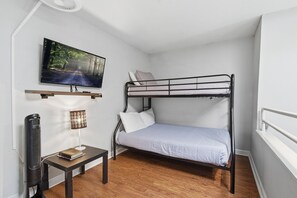 A compact room with a bunk bed, a flat-screen TV mounted on the wall, a small table with a book, and a standing fan. - Fantastic 3-bedroom condo in charming Gatlinburg near Ober Gatlinburg (Gatlinburg)