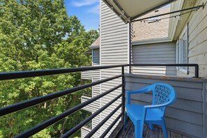 A balcony with a blue plastic chair, metal railing, and a building with horizontal siding in the background. - Fantastic 3-bedroom condo in charming Gatlinburg near Ober Gatlinburg (Gatlinburg)