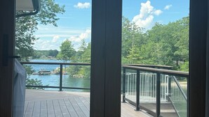 Quarto com vista para um lago, um deck de madeira e guarda-corpo de vidro.