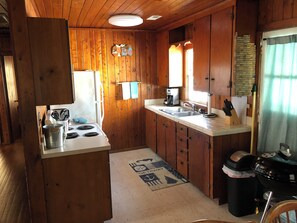 A wooden cabin-style kitchen with a stove, sink, and a coffee maker. - The Retreat of BlackBeard (Kitty Hawk)