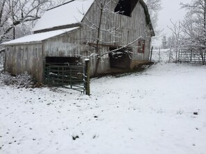Une grange avec une porte en métal et un sol recouvert de neige.
