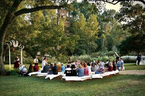 Une réunion en plein air où les participants sont assis sur des bottes de foin, à l’ombre d’un arbre.