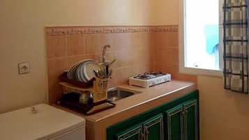 A compact kitchen with a sink, a stove, and cabinets.