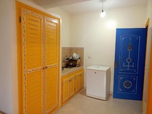 A room with a yellow wardrobe, a white refrigerator, and a blue door with decorative elements.