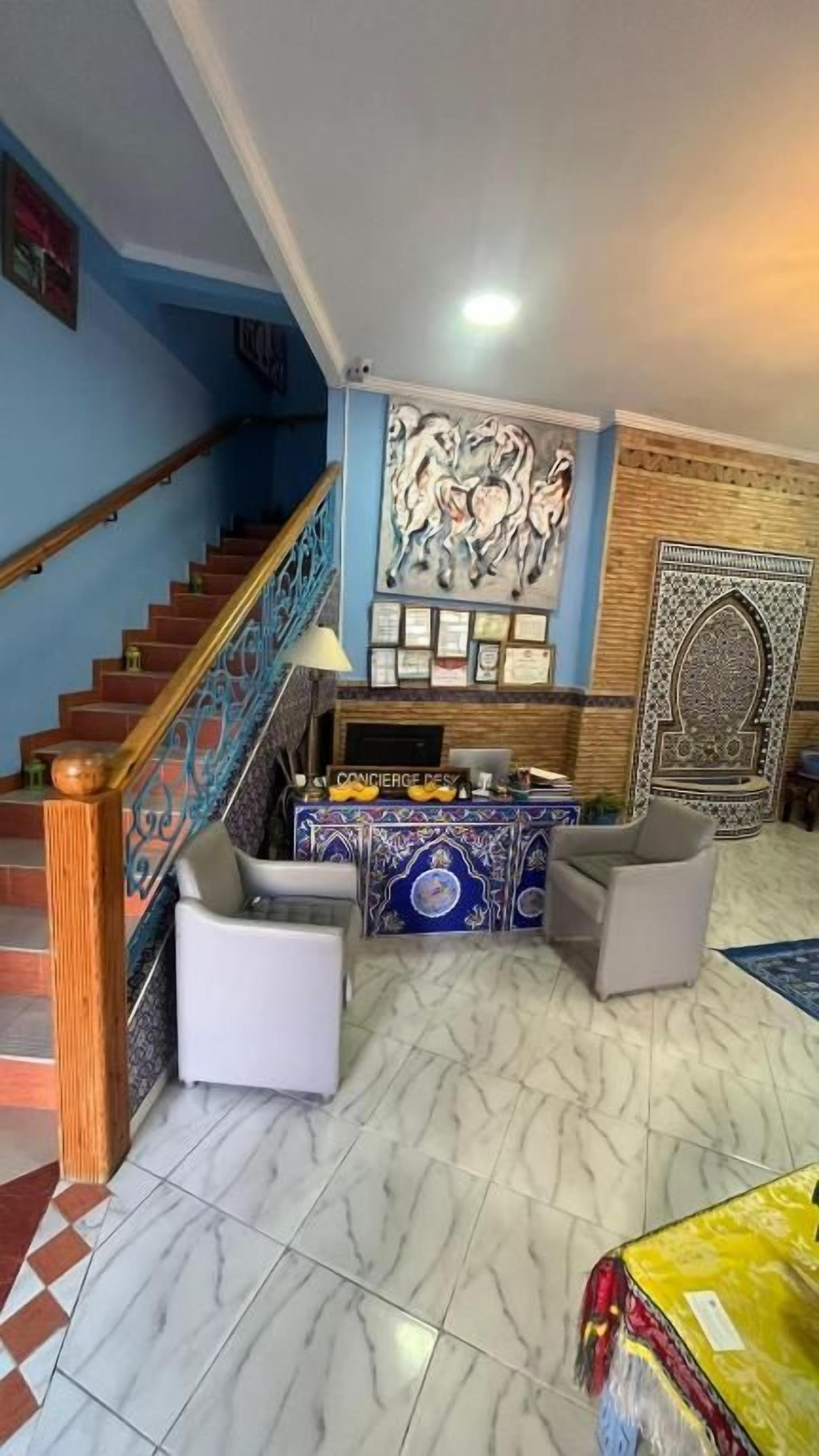 Un salon avec un escalier, un comptoir d’accueil et un mur décoratif.