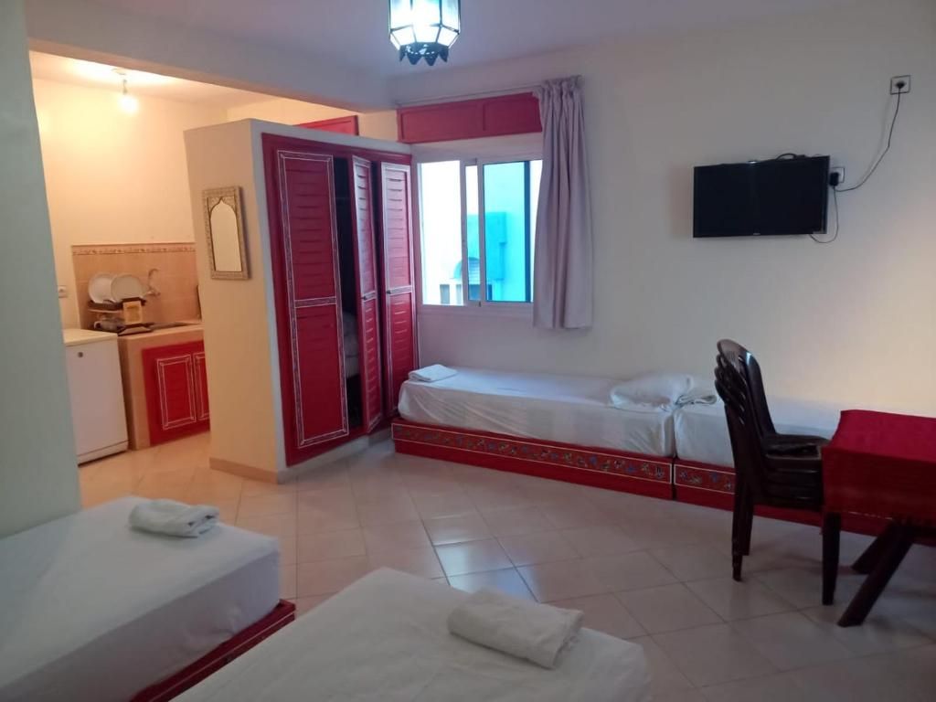 Ein Hotelzimmer mit Bett, Schreibtisch, Stuhl, Fernseher und einem Badezimmer mit Toilette und Waschbecken.