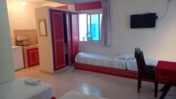 Ein Hotelzimmer mit Bett, Schreibtisch, Stuhl, Fernseher und einem Badezimmer mit Toilette und Waschbecken.