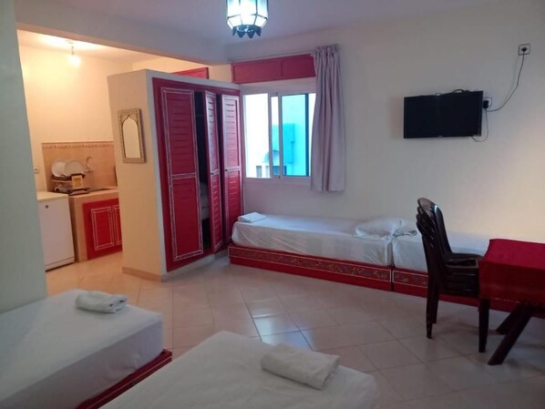A hotel room with a bed, a desk, a chair, a TV, and a bathroom with a toilet and sink.