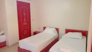 A room with two beds, a red door, and an air conditioning unit.