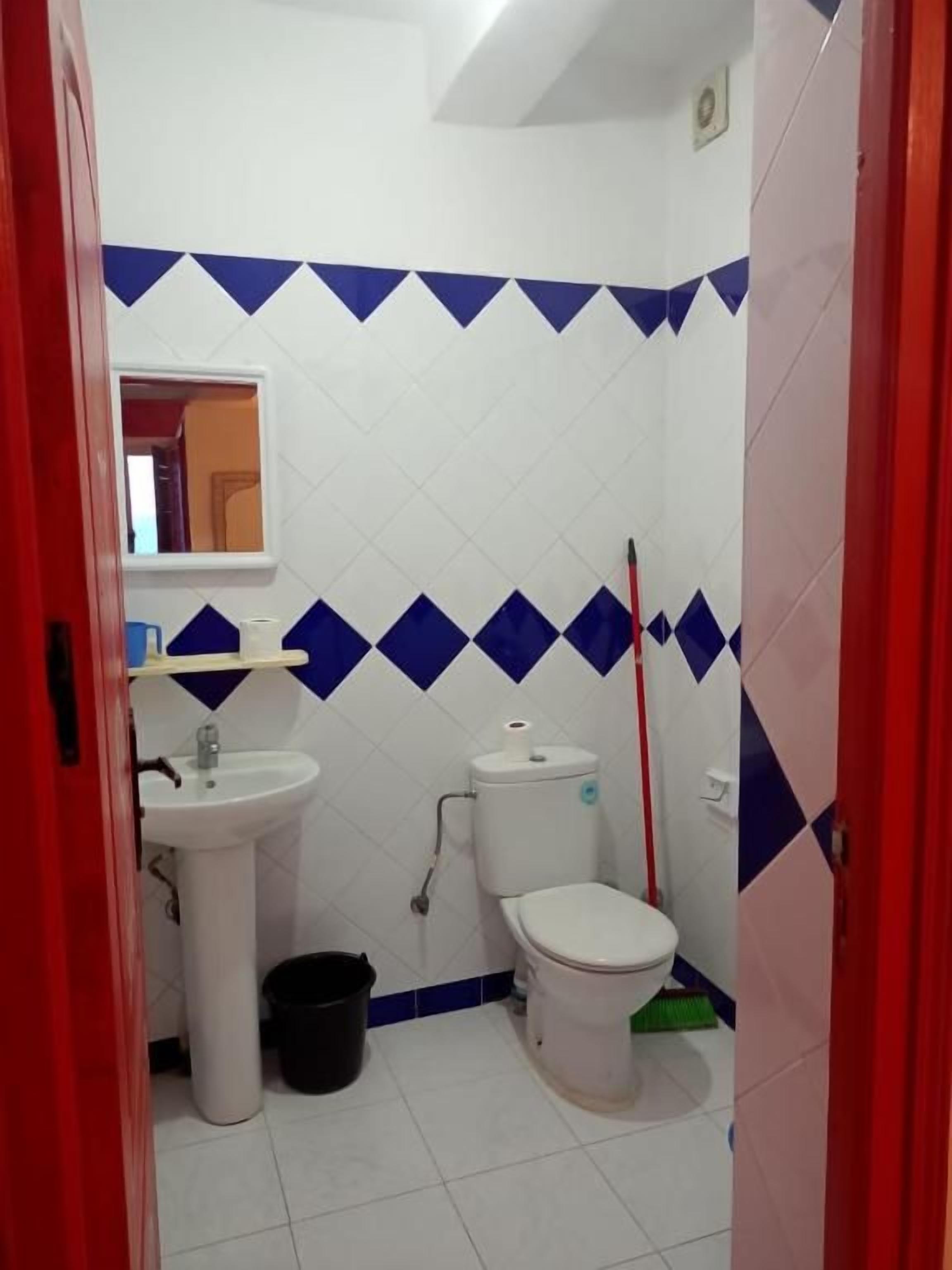 A small bathroom with a white sink, toilet, and a mirror above the sink.