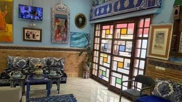 Ein Wohnzimmer mit einer Deckenleuchte, einem blauen Sofa und einem Fernseher an der Wand.