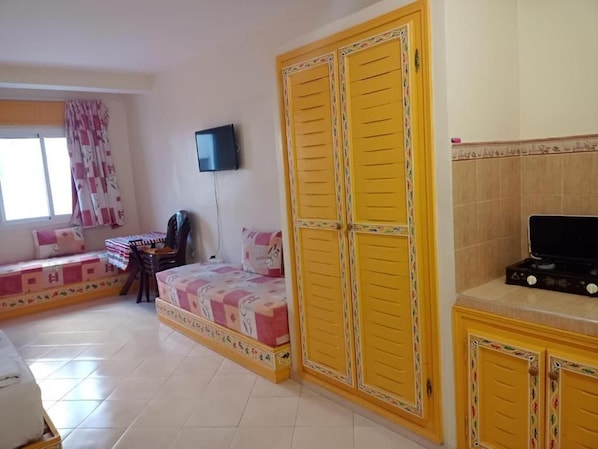 A bedroom with a bed, a desk, a chair, a television, and a wardrobe.