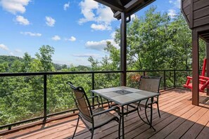 A wooden deck with a table and chairs, overlooking a forested area. - Epic Views | Hot Tub | Minutes to Pigeon Forge (Sevierville)